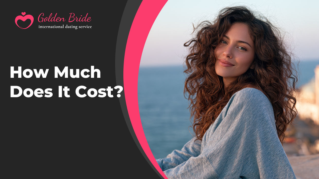 Smiling woman with curly hair in a grey sweater sitting by the sea